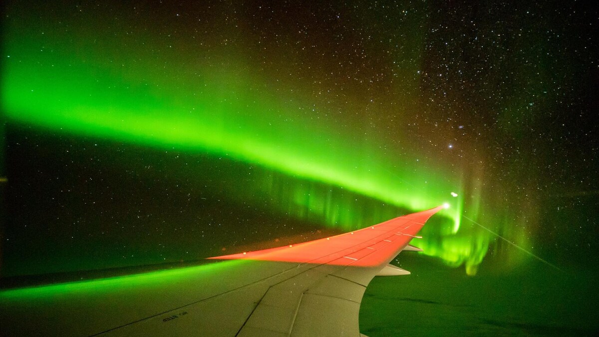 aurores australes aperçues au bout de l'aile d'un avion