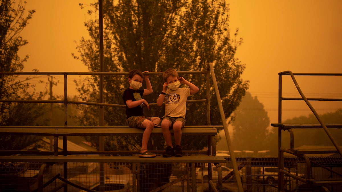 Deux enfants portent des masques tout en jouant sous un épais nuage de fumée.