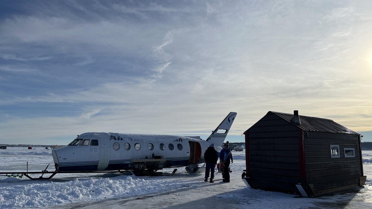 Un avion, sur un lac glacé, près de deux personnes