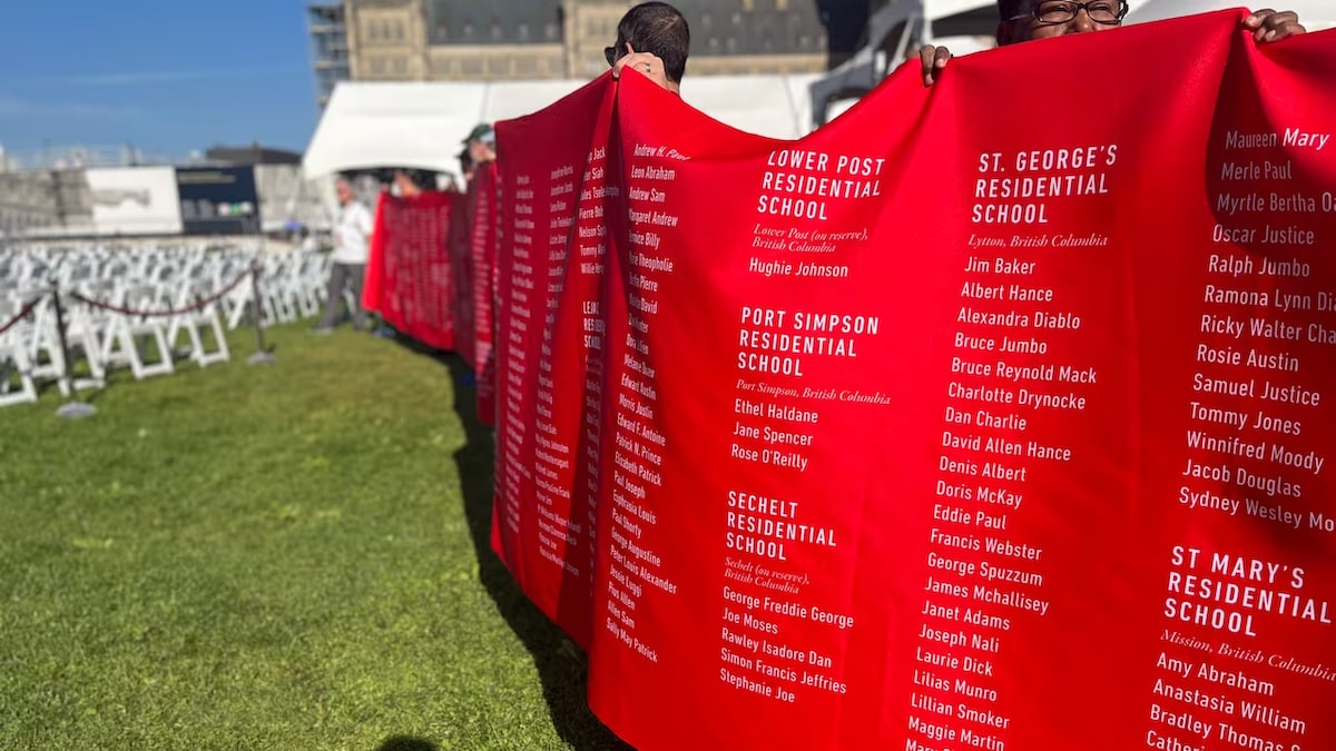 Des personnes tiennent une bannière qui porte les noms de milliers d'enfants.