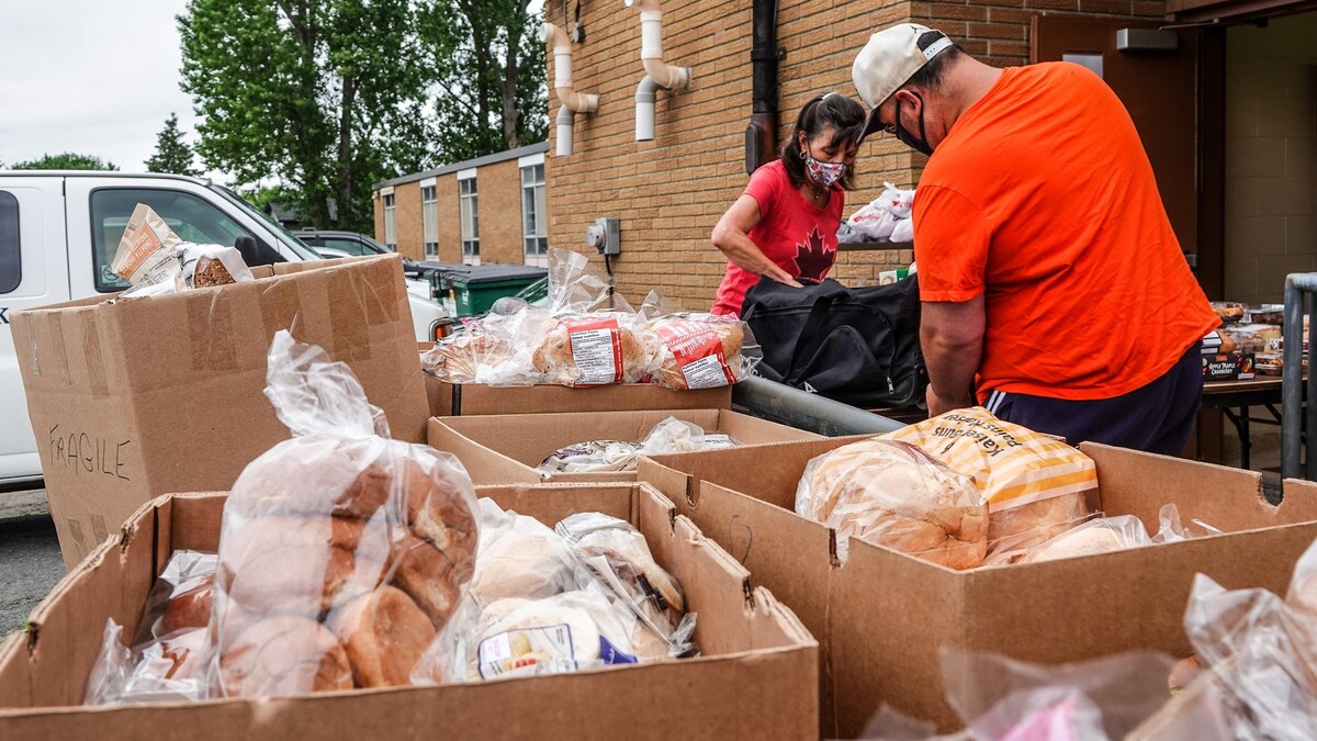 Une bénévole donne des denrées alimentaires à une personne.