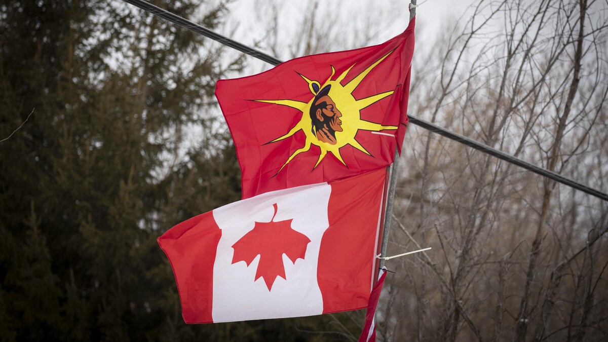 Le drapeau mohawk flotte au-dessus d'un drapeau du Canada placé à l'envers.