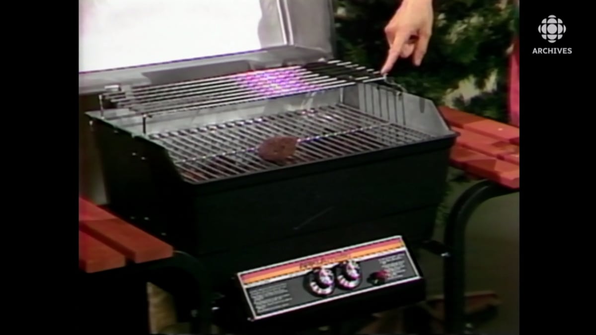 Un doigt pointe un modèle de barbecue avec deux brûleurs et deux tablettes sur le côté.