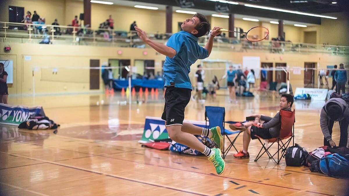 Un jeune joueur de badminton saute pour attaquer le volant.