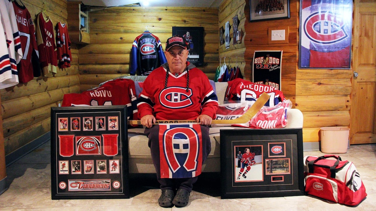 Un homme vêtu d'un chandail et d'une casquette des Canadiens de Montréal est entouré d'objets à l'effigie de l'équipe dans son sous-sol.