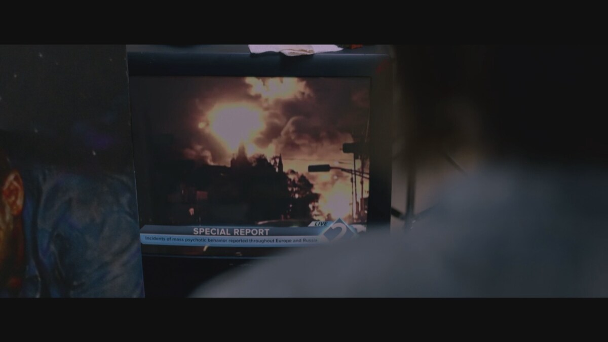 Une personne regarde un écran de télévision où une explosion se produit. 