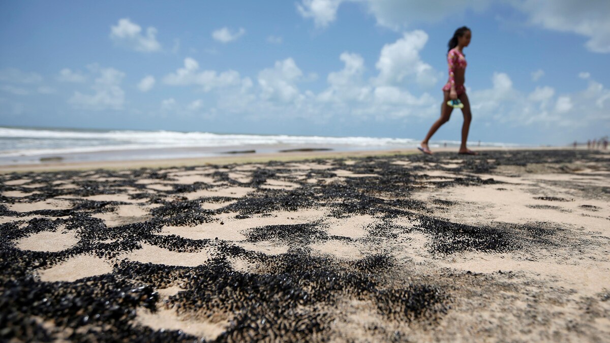 Une personne marche sur le sable noirci.