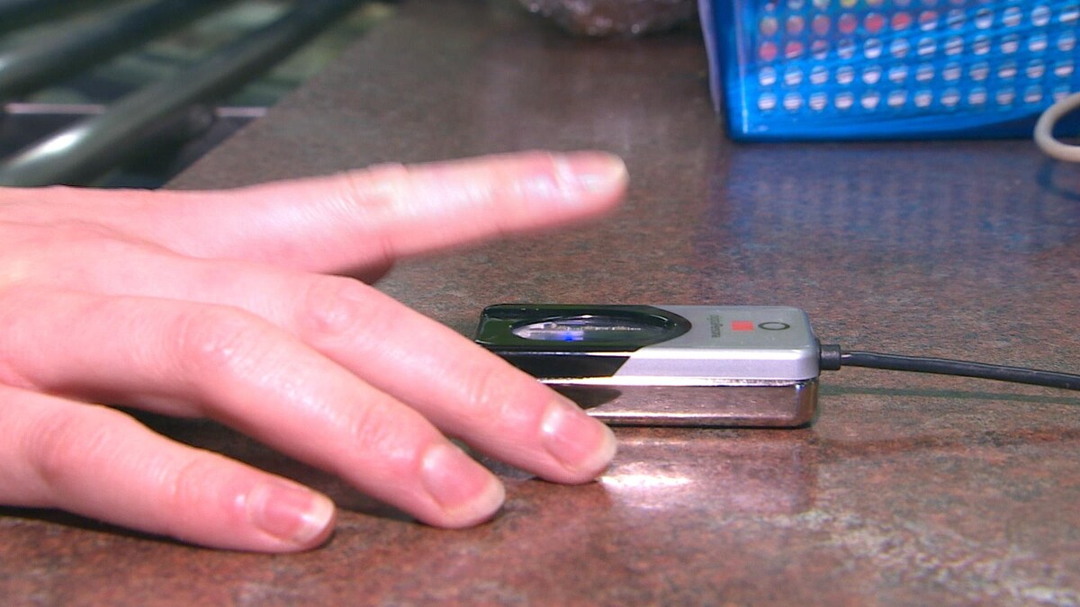 Une main sur un lecteur biométrique.