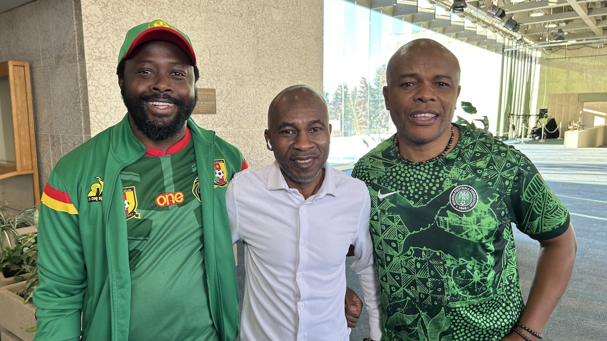 Trois hommes souriants se tenant par le bras.