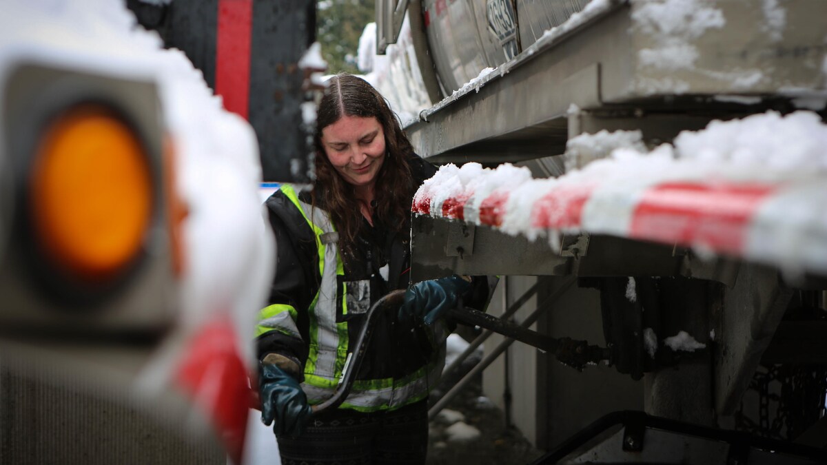 Alicia Kerfoot utilise un outil entre deux camions. 