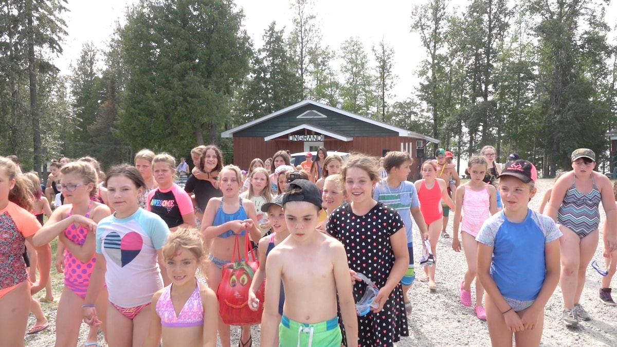 Des jeunes marchent en maillot de bain devant le camp.