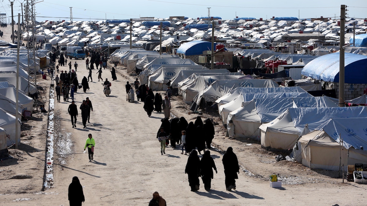 Vue aérienne d'un camp. On voit de nombreuses tentes blanches et des gens, notamment des femmes couvertes de la tête au pied, marcher dans une allée.