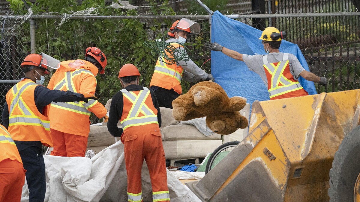 Des employés démantèlent un campement de fortune à Montréal.