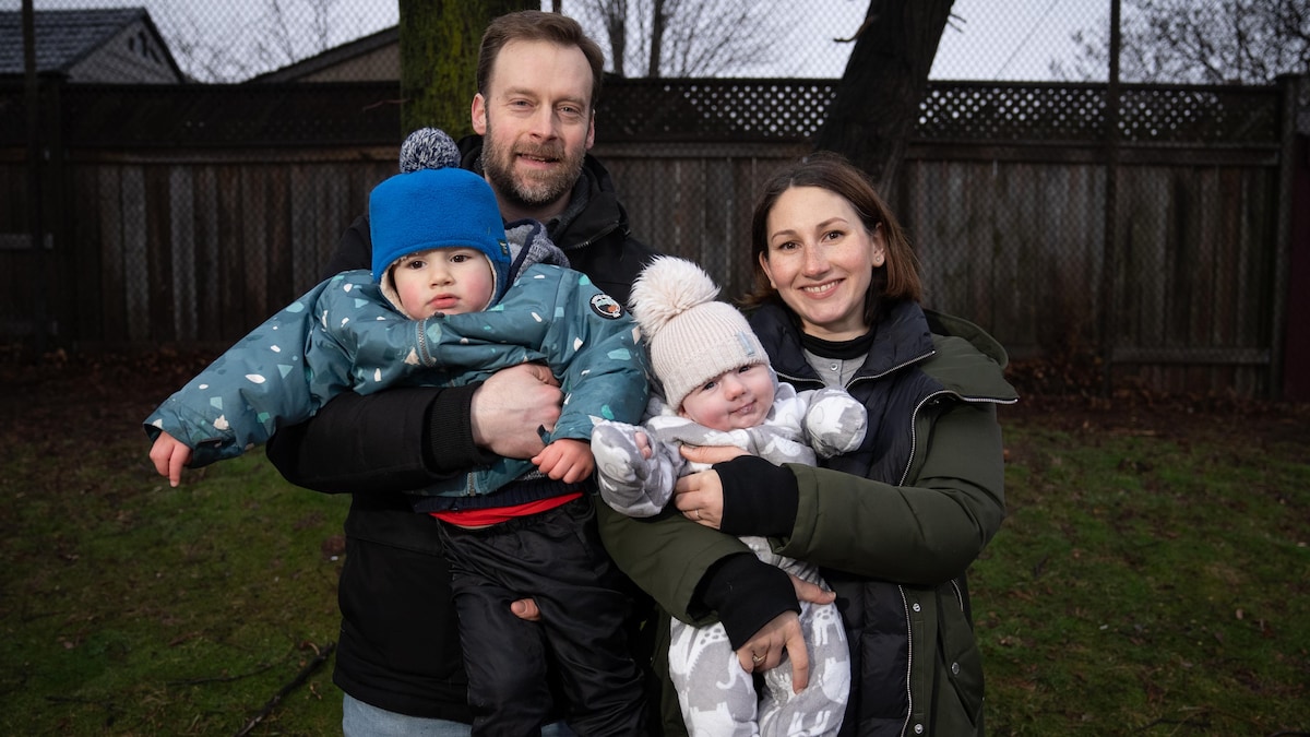 Emma Kenyon et Daniel Warelis posent pour la caméra avec leurs deux enfants dans les bras dans un parc de Toronto.