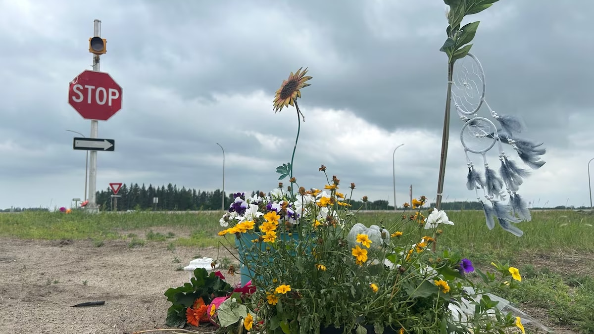 Des fleurs et des objets forment un mémorial près d'une intersection d'autoroute.
