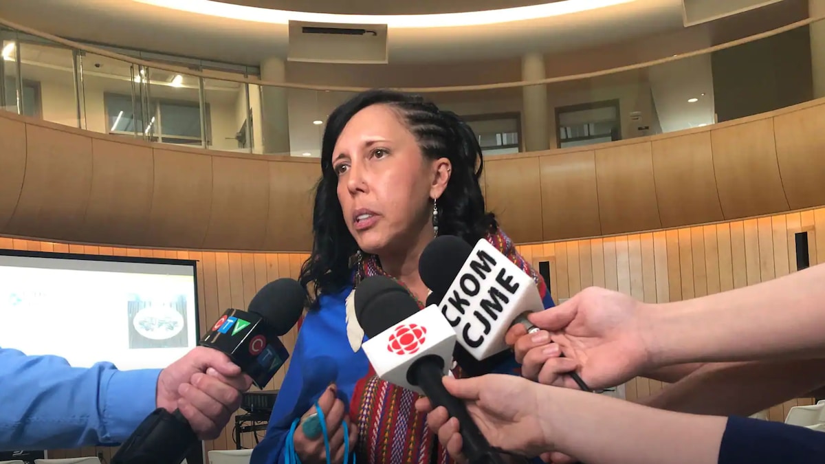 Carrie Bourrassa répond à des questions de journalistes dans un auditorium. 