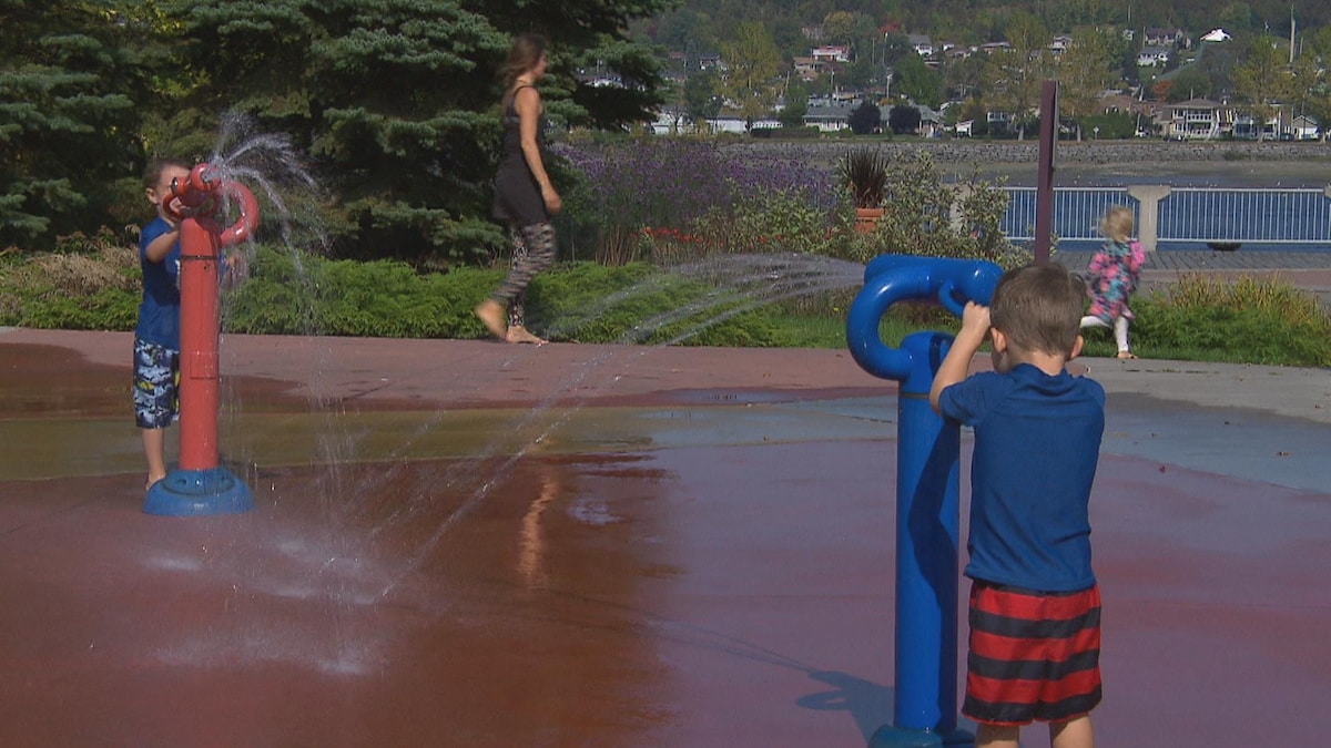 Deux enfants s'amusent dans les jeux d'eau à Saguenay.