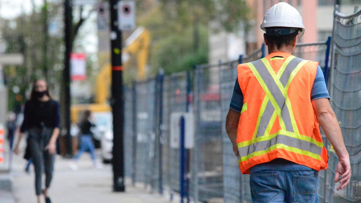 Un ouvrier d'un chantier de construction marchant dans une rue à Montréal.
