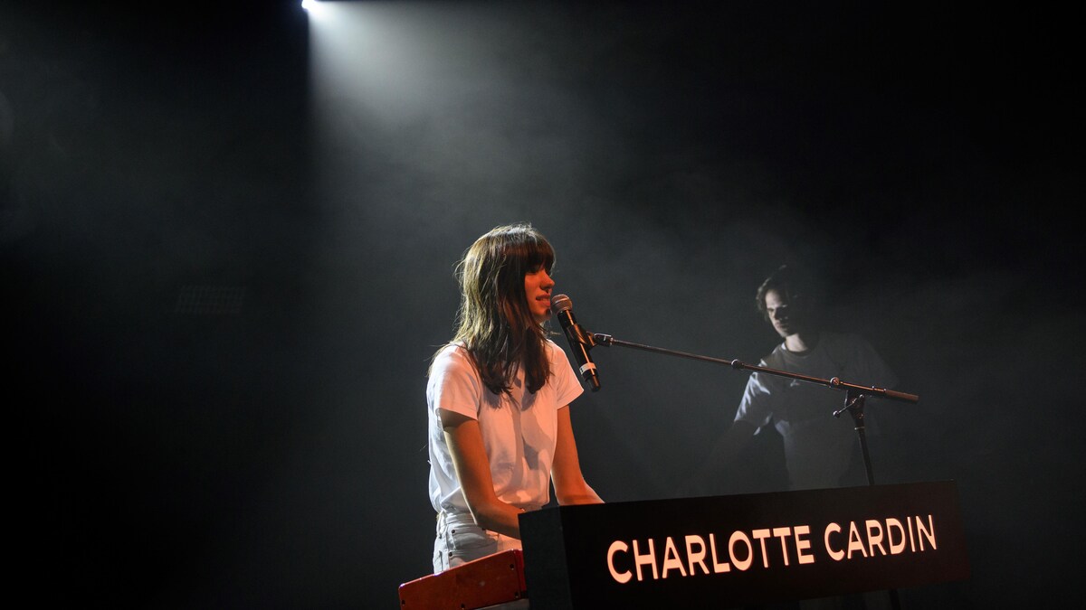 La chanteuse Charlotte Cardin, au clavier, dans le noir, sur une scène.