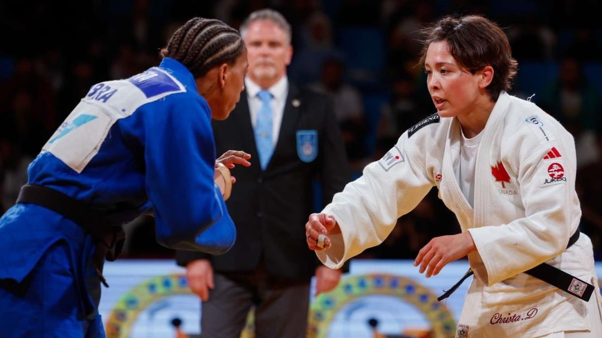 Deux athlètes de judo se regardent pendant un combat, les bras en avant.