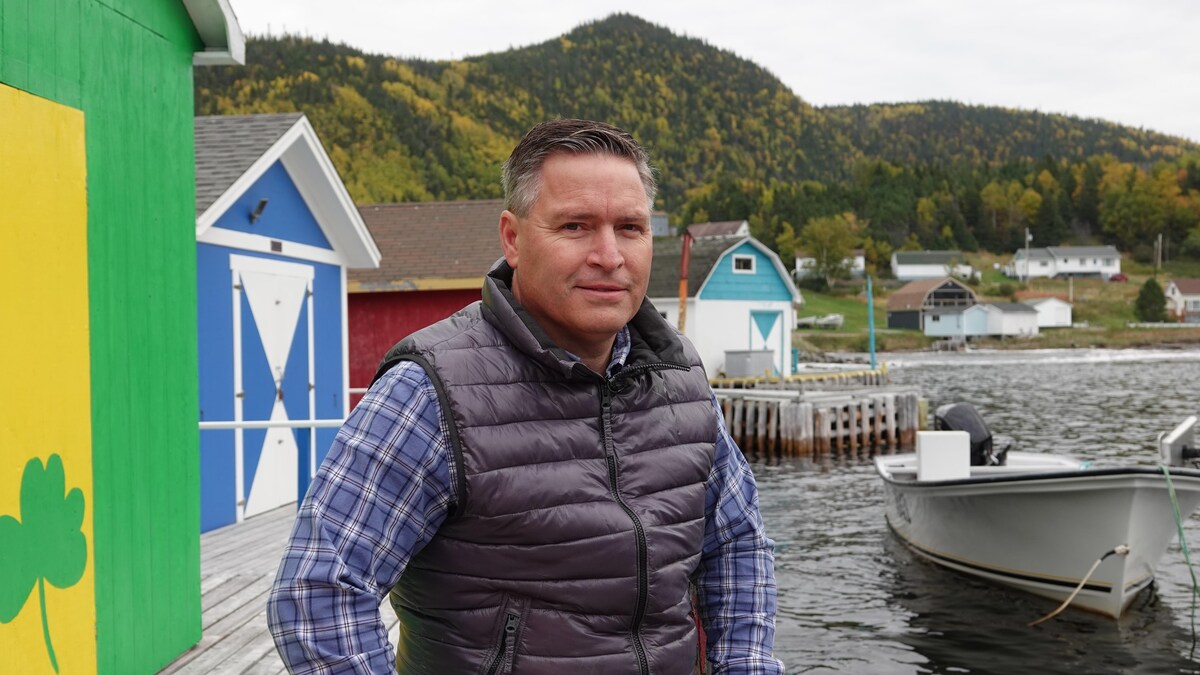 Portrait de Clifford Small sur un quai. Des maisonnettes colorées sont derrière lui.