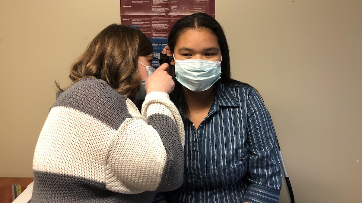 Une infirmière inspecte l'oreille d'une femme autochtone.
