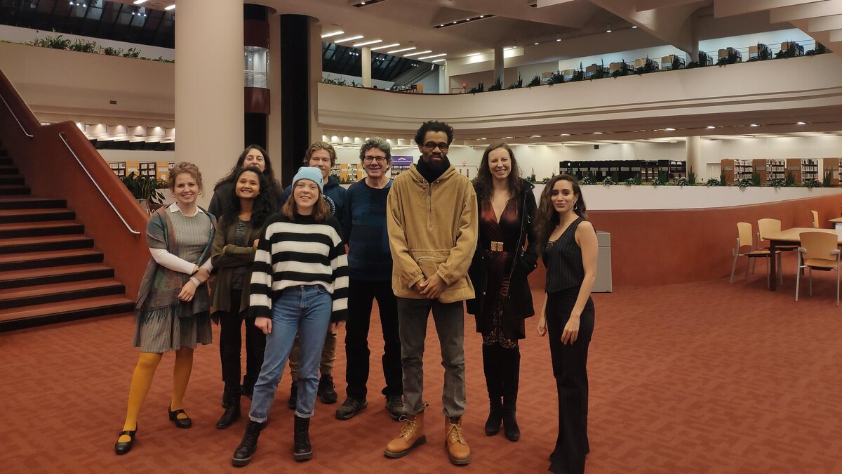 Un groupe de personnes sont debout au milieu de la Bibliothèque de Référence de Toronto.