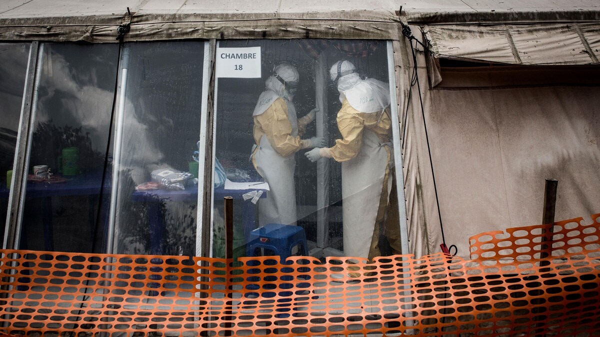 Des médecins en tenue stérile travaillent à l'intérieure d'une tente où l'on traite des patients atteints de l'Ebola.