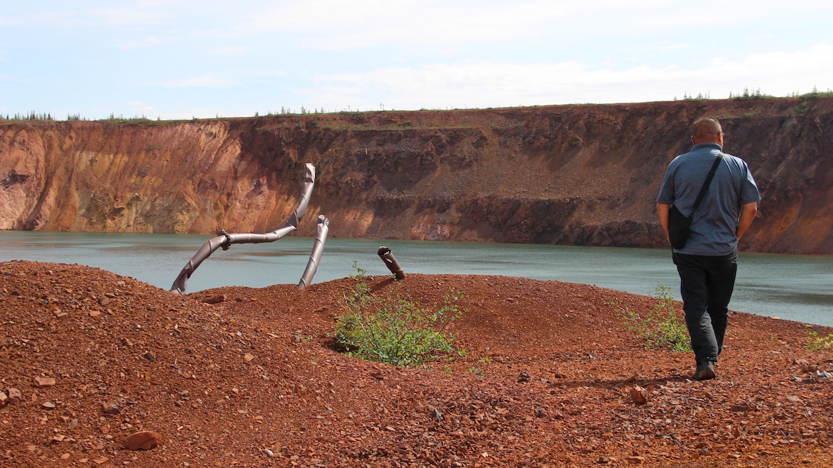 Un homme qui marche de dos au bord d'un trou de mine. 