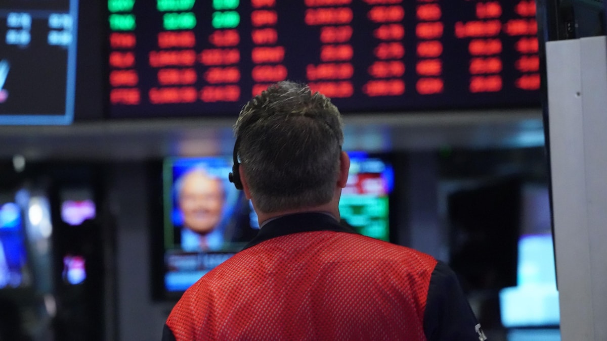 Un courtier regarde les résultats de la Bourse sur un tableau d'affichage numérique.