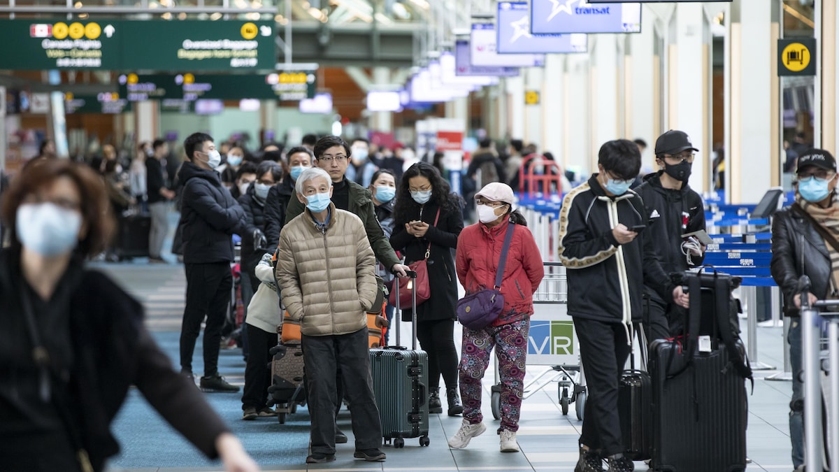 Des passagers portent un masque à l'aéroport de Vancouver.