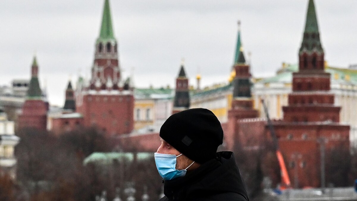 Un homme portant un masque marche sur un pont près du Kremlin.