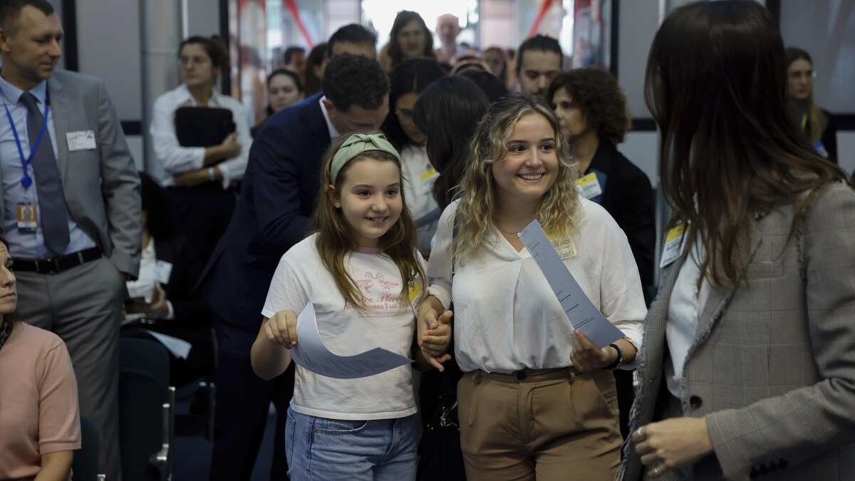 Deux jeunes filles souriantes au milieu d'une foule dans le hall d'entrée d'une cour de justice.