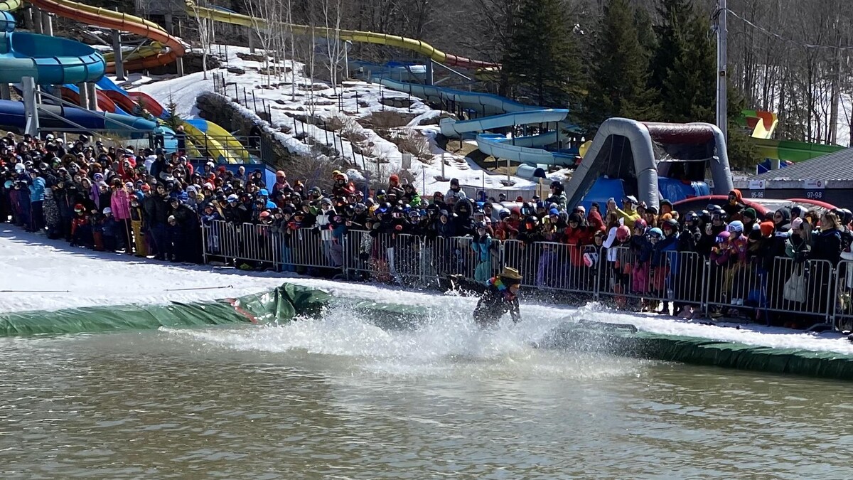 Un participant tente de traverser la piscine sur ses skis sous les regards de centaines de spectateurs. 