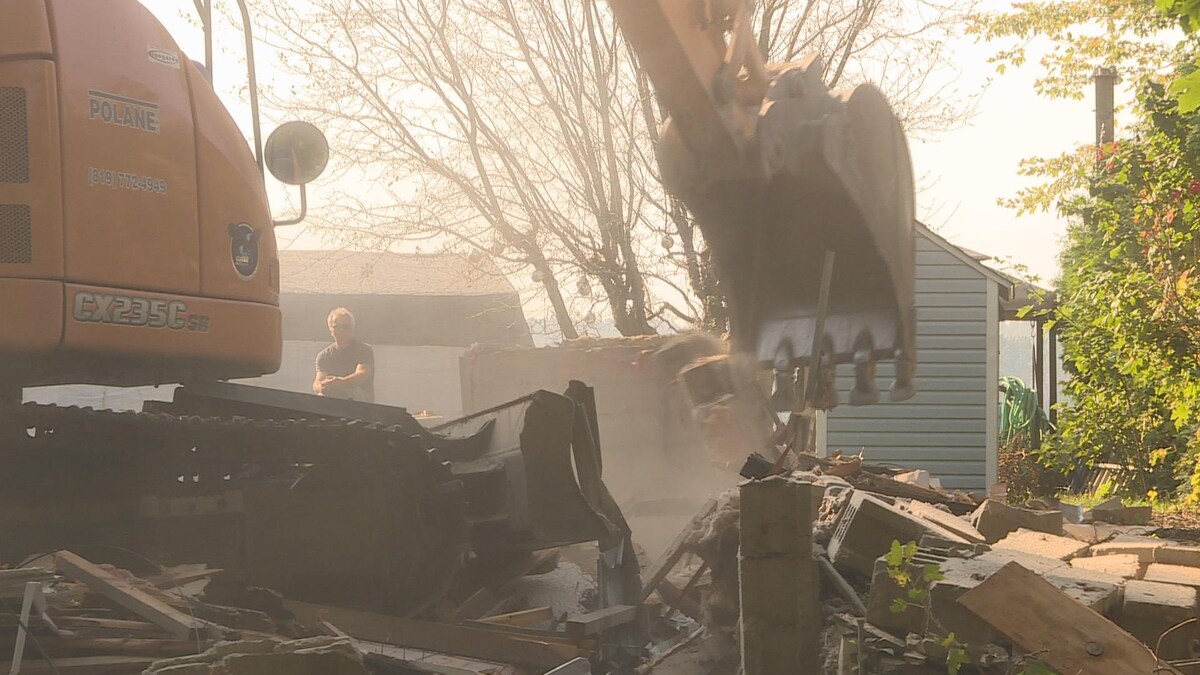Un homme observe à l'arrière plan le travail de démolition
