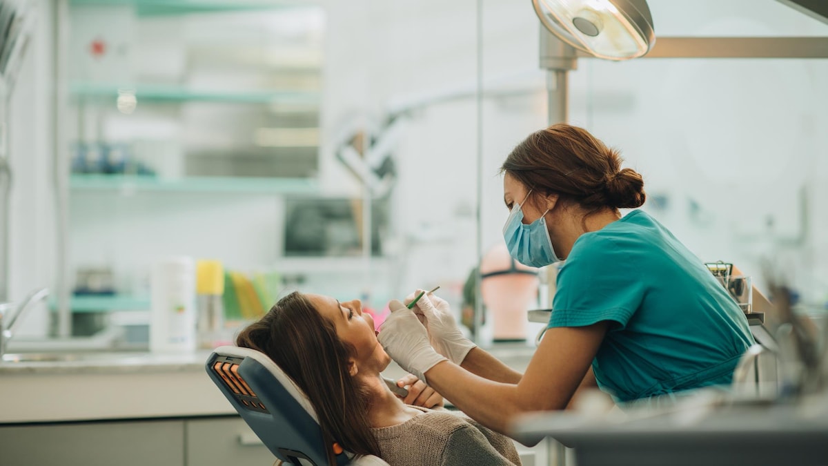 A dentist examines a young woman's teeth.
