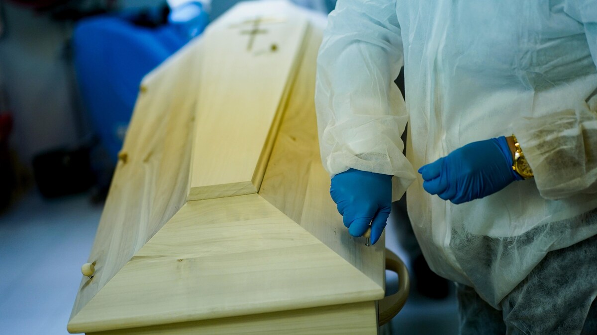 Un employé portant des gants étanches refermant un cercueil. 