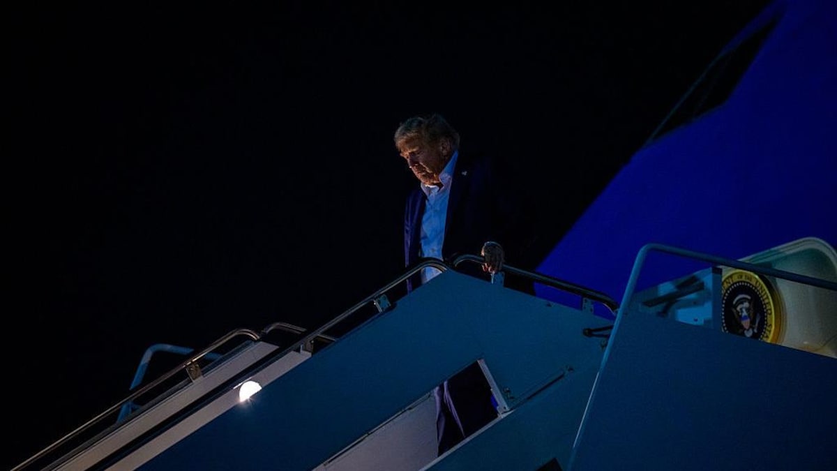 Le président Donald Trump descend d'Air Force One le soir.