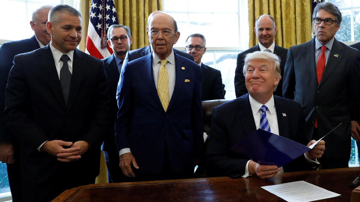Le président américain Donald Trump est assis à son bureau de la Maison-Blanche. Le PDG de la compagnie TransCanada et les secrétaires au Commerce et à l'Énergie se tiennent debout un peu en retrait derrière lui.