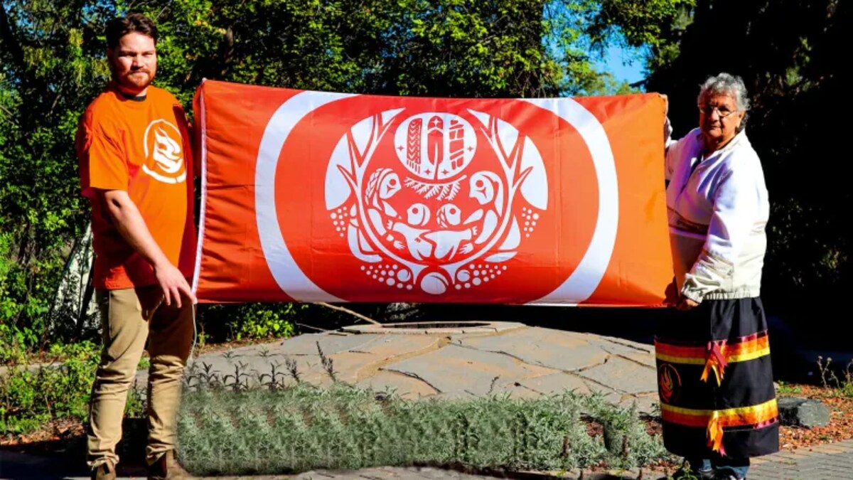 Deux personnes tiennent un drapeau orange.