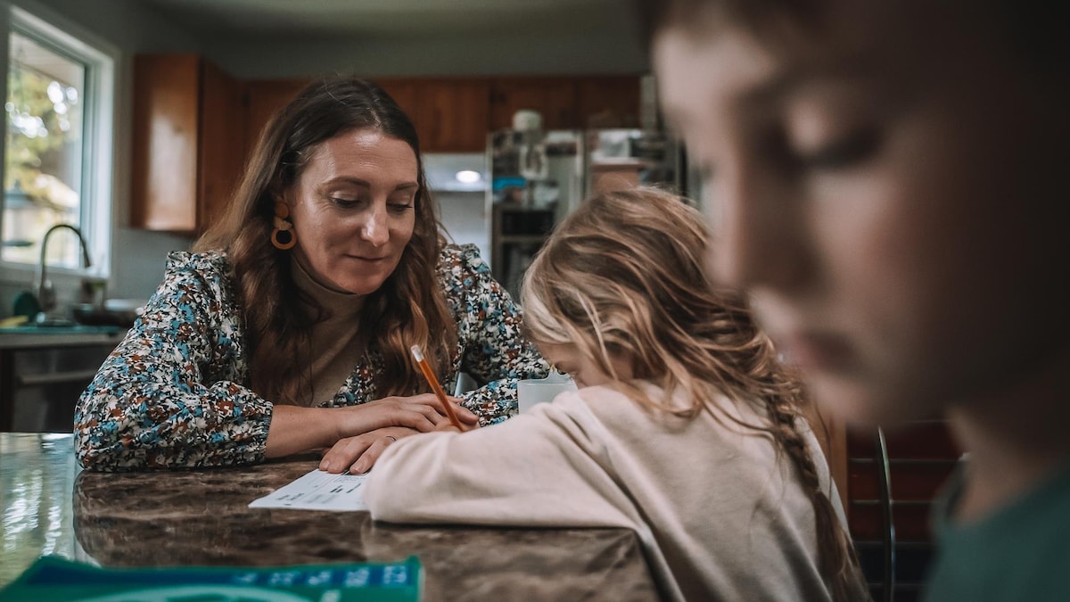 La mère est à la table et enseigne à ses enfants.