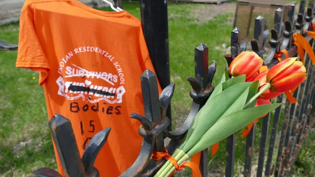 Un chandail orange est suspendu  à côté d'un bouquet de tulipes elles aussi orange. 