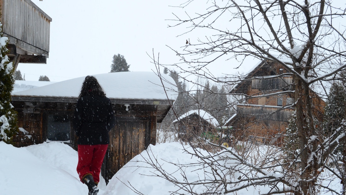 Dans un paysage hivernal, une femme marche à travers des maisons de style alpin