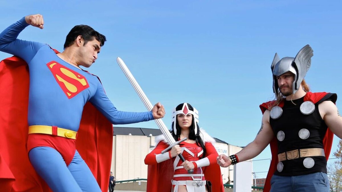 Trois personnes déguisées en costume de Superman et Thor prétendent de se battre.