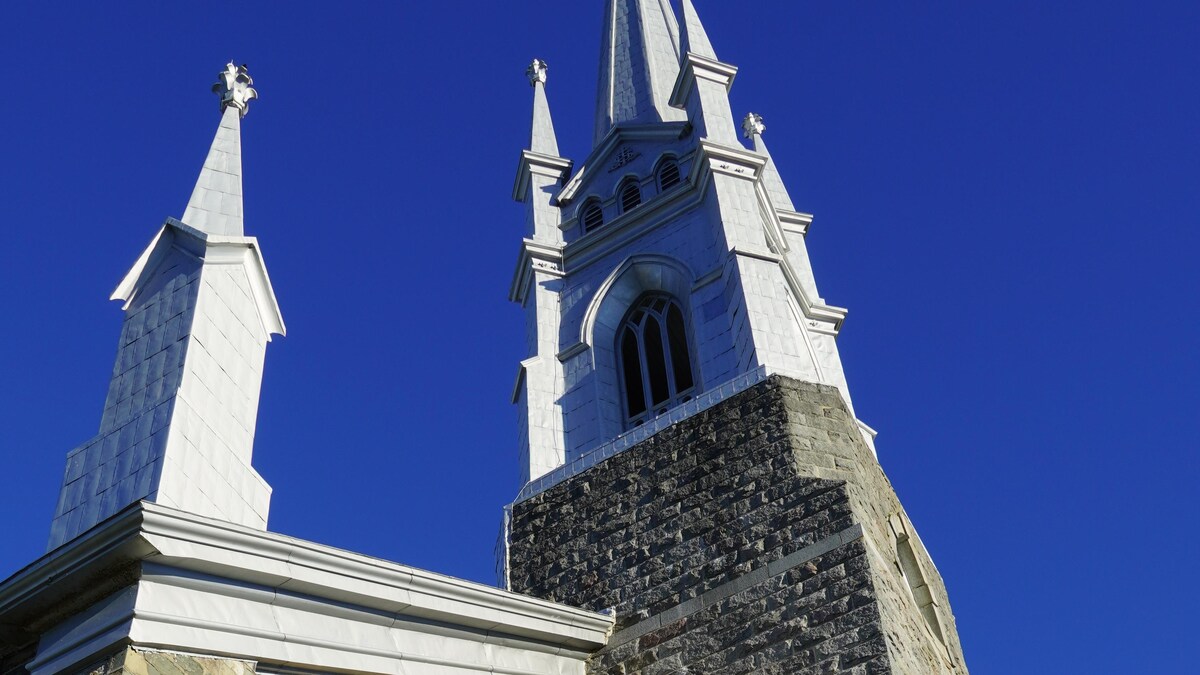 Vue en contre-plongée du clocher de l'église de L'Isle-Verte lors d'une journée ensoleillée.