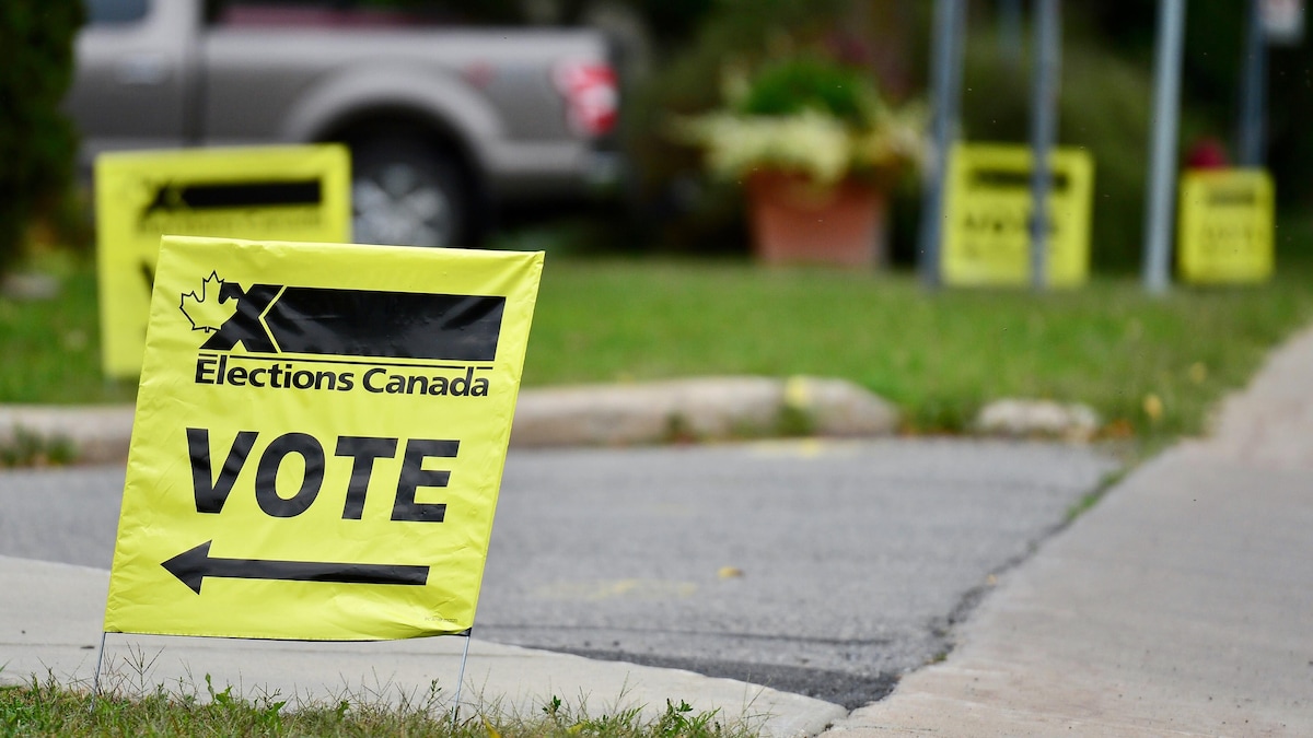 Des affiches d'Élections Canada indiquent la direction de l'entrée d'un bureau de vote.