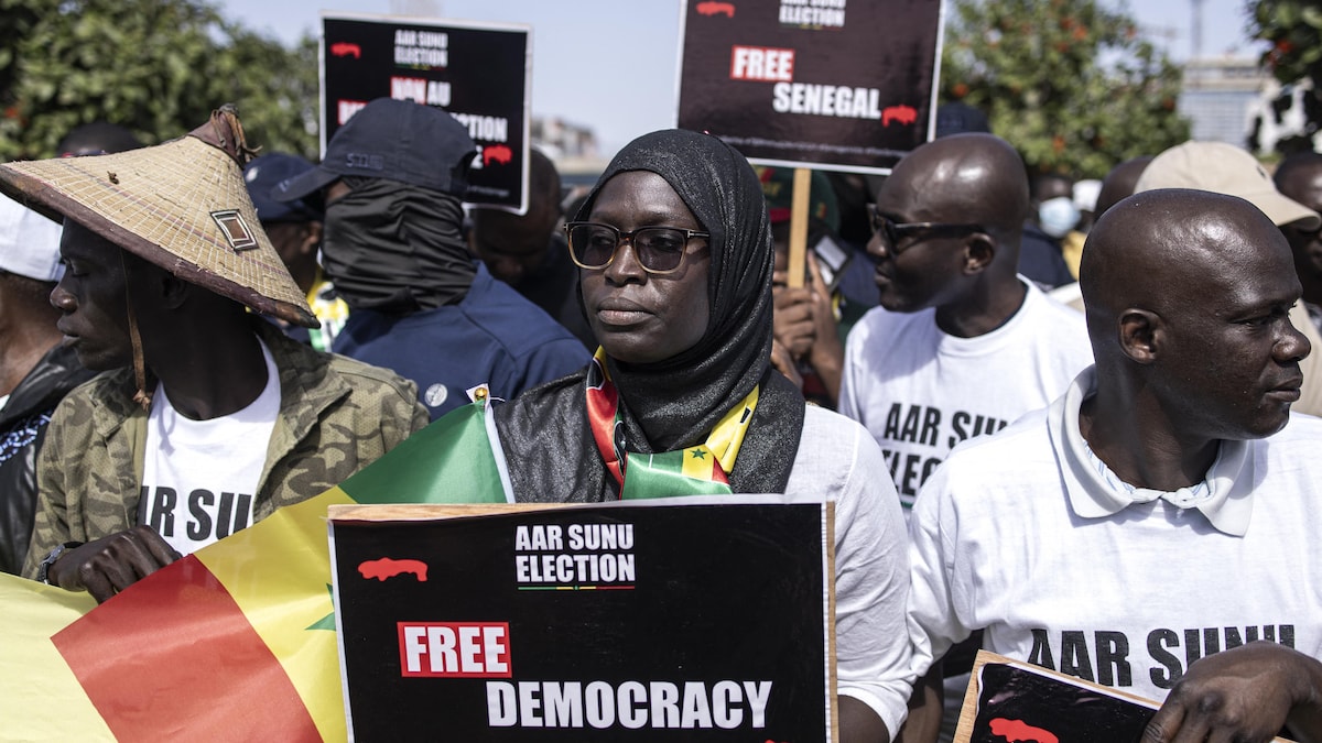 Des personnes marchent lors d'une manifestation et tiennent des pancartes sur lesquelles il est écrit en anglais "Démocratie libre". 
