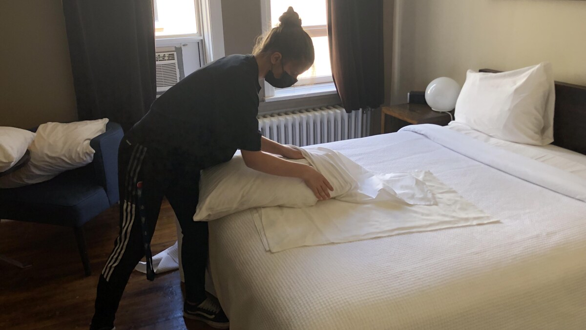 Une employée plie des draps sur un lit.
