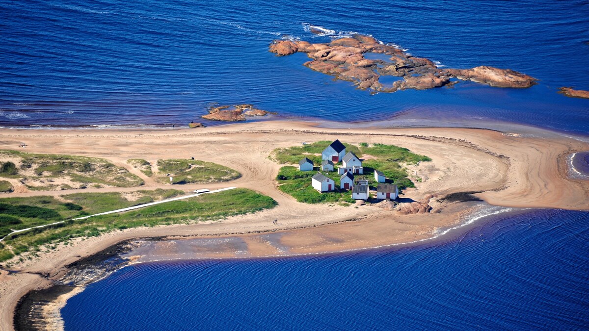 Vue aérienne d'une péninsule ensablée avec des petites maisons.