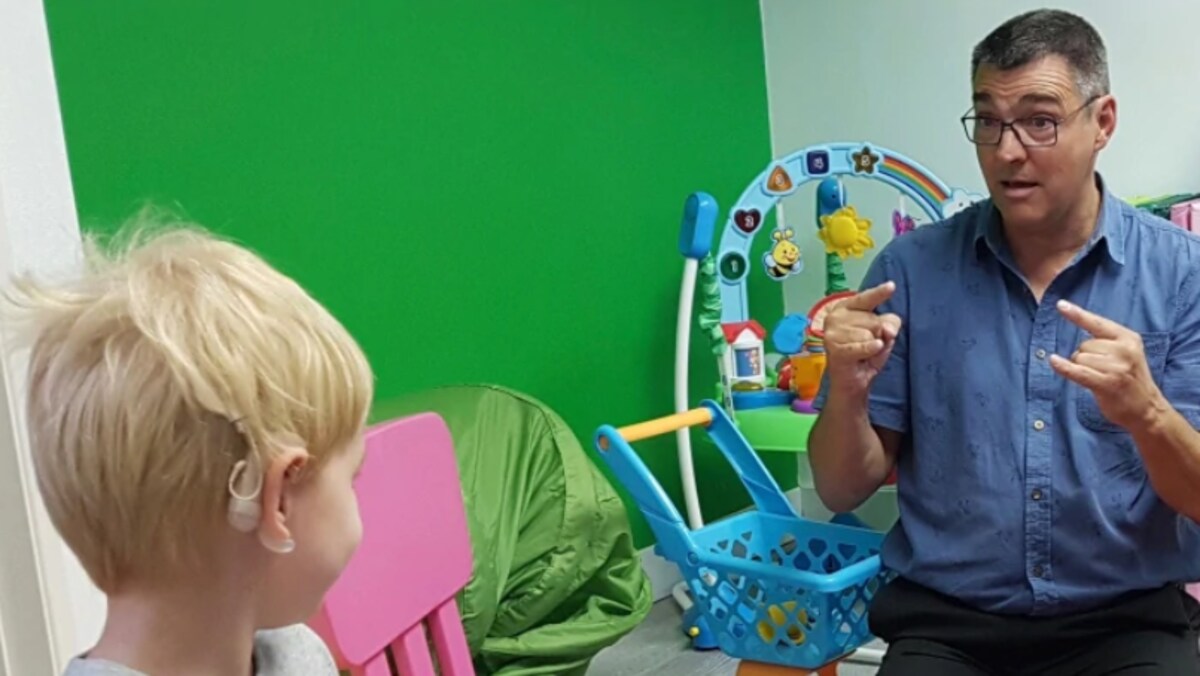 Un enfant  apprend le langage des signes avec Nairn Gillies des Services pour sourds et malentendants qui lui montre avec ses mains comment communiquer avec le monde extérieur.